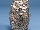 a silver owl figurine sitting on top of a blue surface