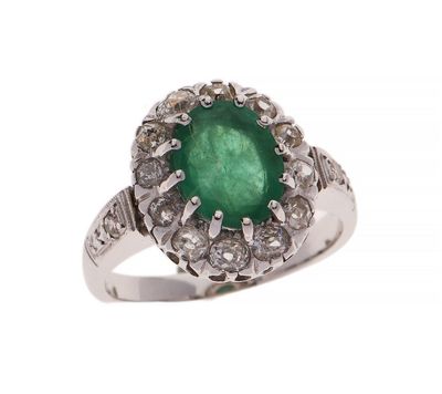 gros plan d'une bague avec une pierre verte entourée de diamants