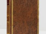 un livre en cuir marron avec des finitions dorées, y compris sur la couverture
