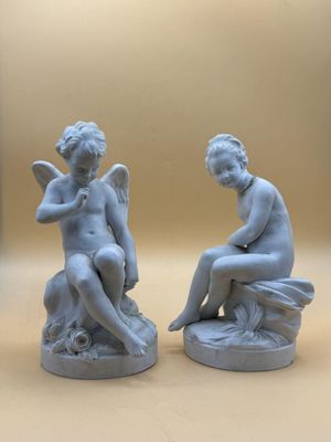 une paire de statues représentant un garçon et une fille assis sur un rocher