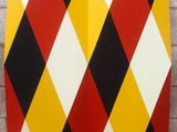 yellow, red, black and white argyle pattern on a brick wall