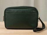 a green cross body bag sitting on top of a wooden table