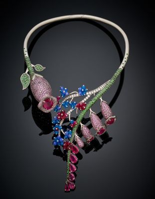 a close up of a necklace with flowers and leaves on it