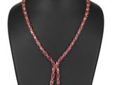 un collier composé de perles roses et d'un pompon, posé sur un mannequin