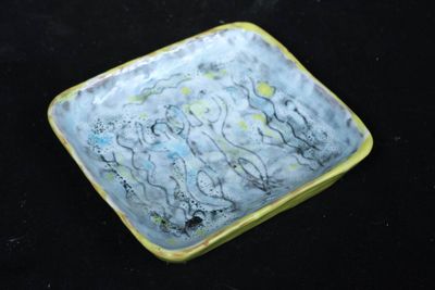 une assiette jaune et bleue posée sur une surface noire