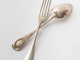 two silver spoons and a fork on a table