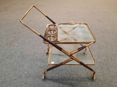 un chariot de bar en verre et en laiton posé au sol