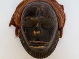 un vieux masque en bois accroché au mur d'une pièce blanche