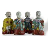 trois figurines représentant des hommes asiatiques sont assises sur une surface blanche