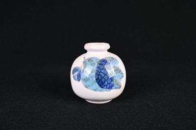 un petit vase blanc orné d'un poisson bleu