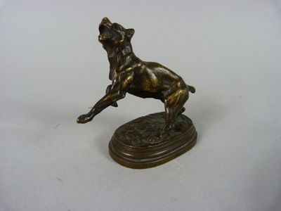statue en bronze représentant un chien bondissant, posée sur un socle, sur une surface blanche