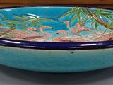 a bowl with a bird sitting on top of it on a table