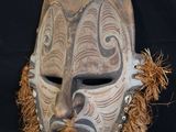 an image of a wooden mask with feathers on it