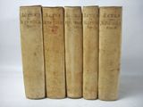 four old books sitting on top of each other on a white surface