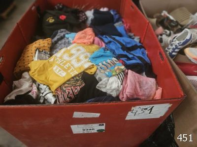 une boîte rouge remplie de vêtements et de chaussures posée par terre