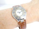 a wrist watch on a woman ' s wrist with roman numerals on it