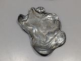 a silver plate with a face on it next to a pair of scissors
