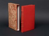 an open red book sitting on top of a table next to a black background