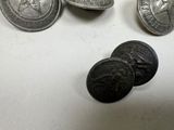 three silver coins and a pair of black buttons on a white surface