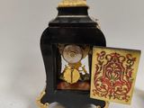 a small clock with a gold figure on top of it
