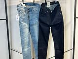 deux paires de jeans suspendues à un portant dans un magasin de vêtements