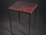 une image représentant une petite table au plateau rouge sur fond noir