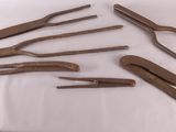 Six paires de pinces sont posées sur une table recouverte d'une nappe blanche.