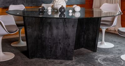 Grande table circulaire à piétement en bois noirci et plateau en verre