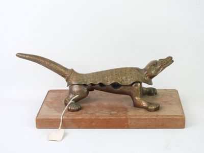 bronze sculpture of a lizard on a wooden base with a tag