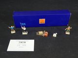 figurines de Tintin dans une boîte bleue posée sur une surface noire
