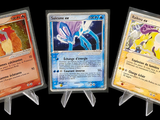 Trois cartes Pokémon différentes sont représentées en rangée sur un fond noir.