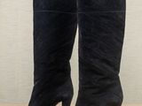 a pair of black sued high heel boots on a wooden floor