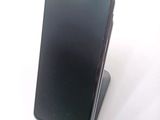 a black cell phone sitting on a stand on a white surface