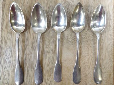 six cuillères en argent sont alignées sur une surface en bois
