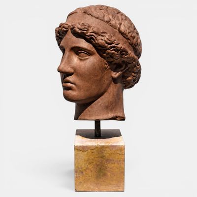 un gros plan sur une sculpture représentant une tête de femme posée sur un socle en bois