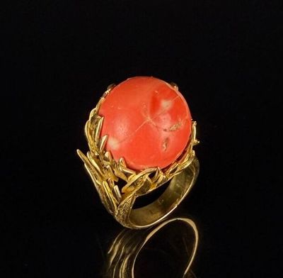 an image of a gold ring with a coral stone in the center