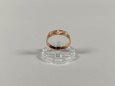 a close up of a gold ring on a clear stand