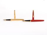 une paire de stylos à bille rouges et dorés sur fond blanc