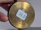 a person holding a small gold clock with a sticker on it