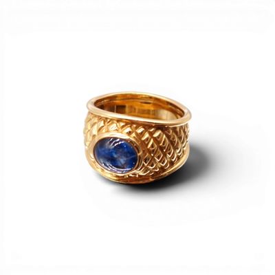 gros plan d'une bague en or avec une pierre bleue