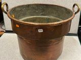 a large copper pot with handles on a table