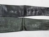une paire de gants en cuir noir posée sur une table blanche