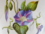 a close up of a plate with a flower painted on it