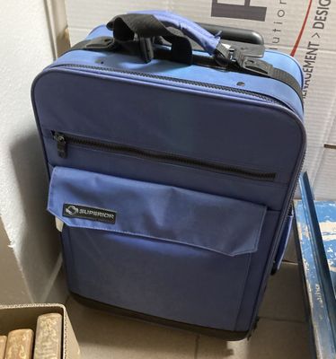 une valise bleue posée par terre à côté d'un carton
