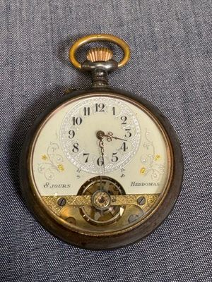 une vieille montre de poche à laquelle est accrochée une chaîne sur le côté