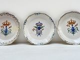trois assiettes avec des motifs de fleurs et de couronnes sur une surface blanche