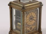 a small brass clock with a glass case on it