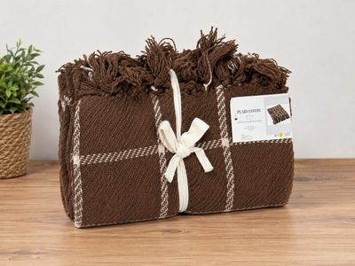 une couverture à carreaux marron et blancs, à laquelle est noué un ruban blanc