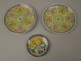 two plates with designs on them are sitting on a wall