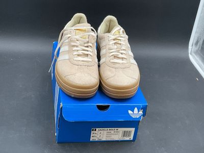beige adidas sneakers on a blue box on a grey surface